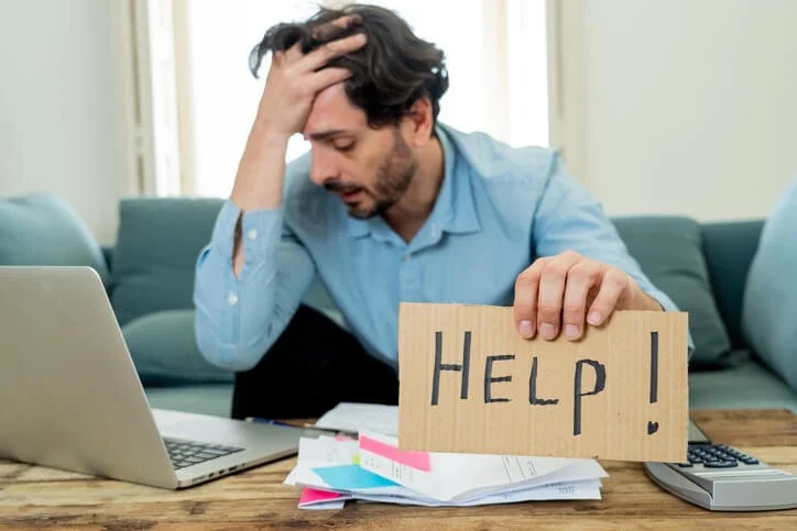 young angry and worried man working with laptop at home looking at bills and paying bills in home finance concept